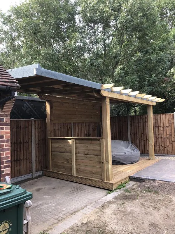 A decked, covered pergola area with storage, and a block patio